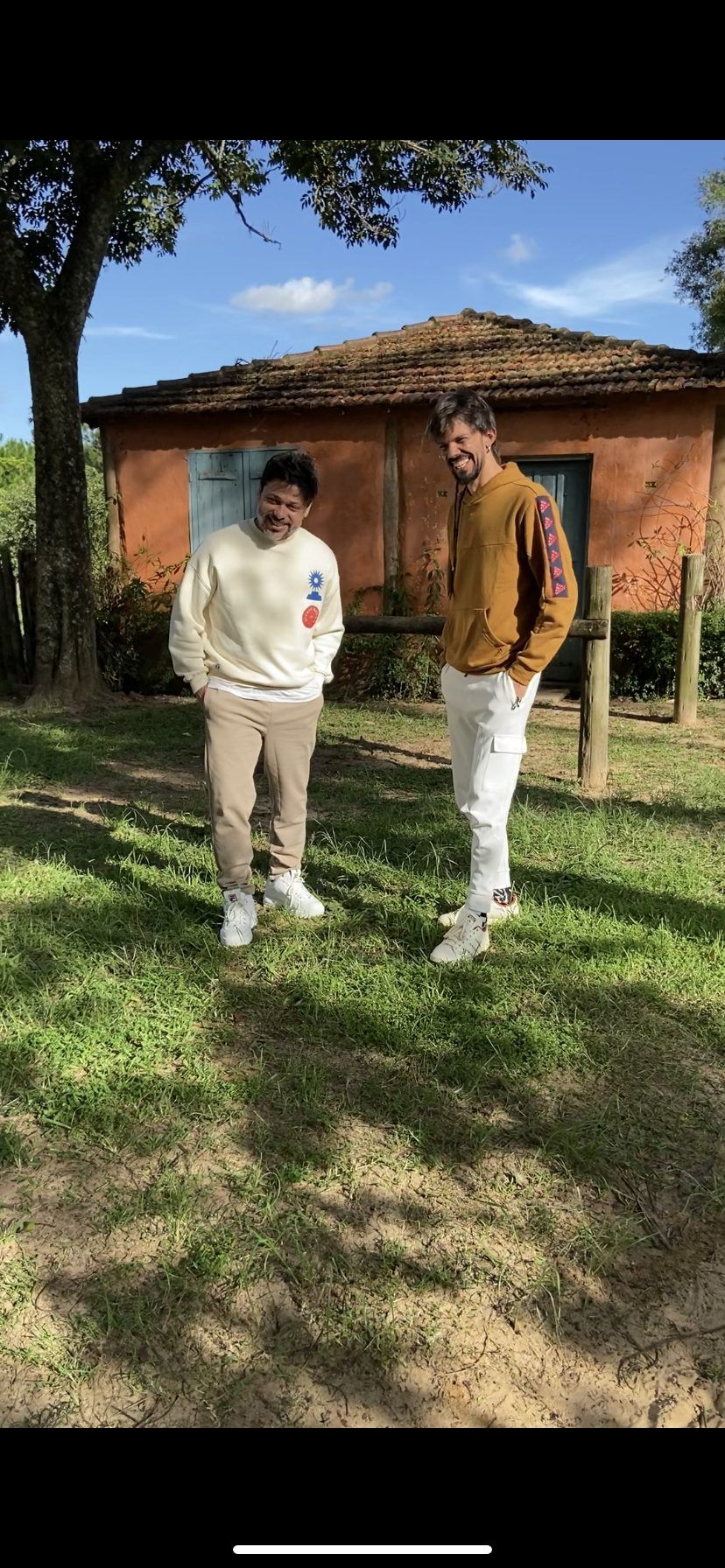 Salomão Soares and Guegué Medeiros in front of a house with an orange wall