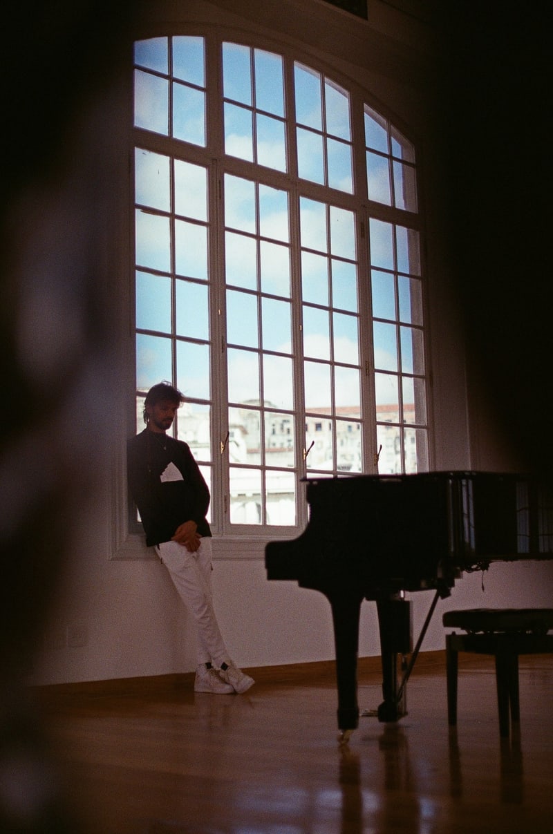 Salomão Soares beside the piano, backlit by a window