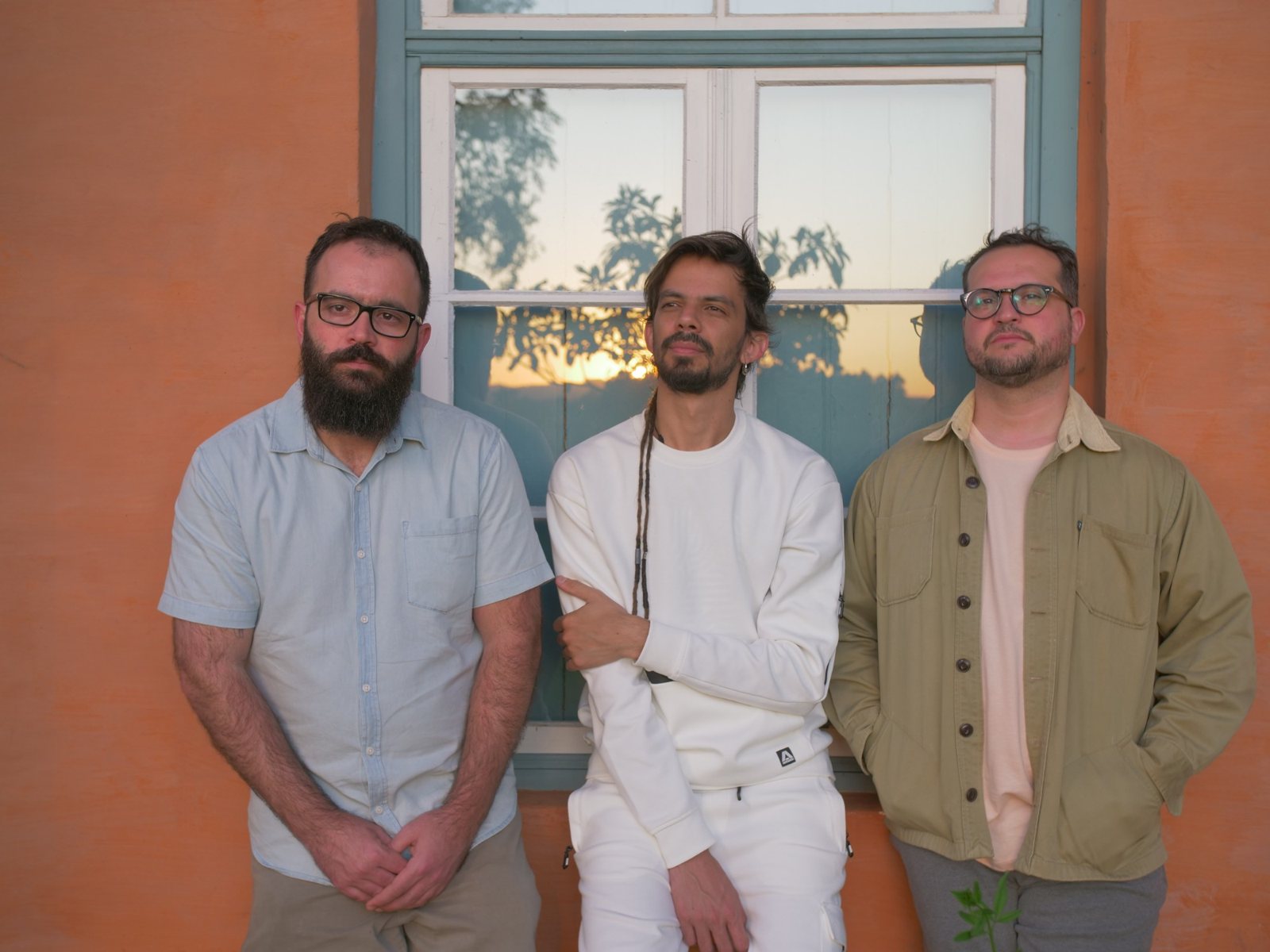 Salomão Soares Trio diante de uma janela, no fim da tarde
